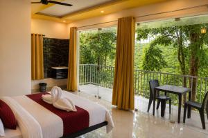 a bedroom with a bed and a balcony at T Hill Vythiri Pool Resort in Vythiri