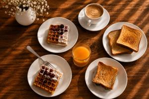 a table with plates of waffles and a cup of coffee at Residence Kazbegi in Kazbegi