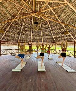 a group of women doing a yoga pose in a gym at Gavana House in Mfumbwi