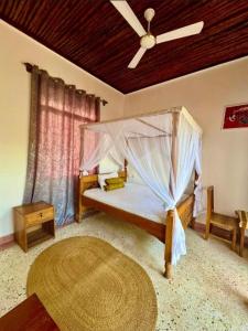 a bedroom with a canopy bed with a ceiling fan at Gavana House in Mfumbwi