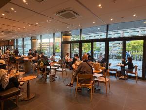 a group of people sitting at tables in a restaurant at WUMETEI Japanese-style lodge in Kyoto