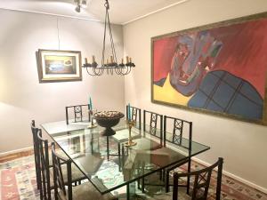 a dining room with a glass table and a painting at Avenida Las Heraas in Buenos Aires