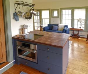 a kitchen with a counter top and a living room at Whitford House Cottage in Addison