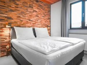 a bed in a bedroom with a brick wall at Seeblick am Pressegger See in Lake Pressegg