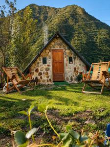 a stone cabin with two chairs and a wooden door at Ebenezer Salkantay Huts in Colcapampa