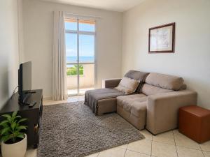 a living room with a couch and a television at Bela vista a beira mar in Marataizes
