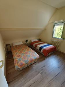two beds sitting in a room with wooden floors at Maison de charme 209m2 in Coray