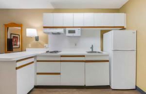 a kitchen with white cabinets and a white refrigerator at Extended Stay America Select Suites - Jacksonville - Baymeadows in Sunbeam