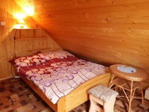 Cama en habitación de madera con mesa y taburete en Chalupa Tália, en Liptovský Mikuláš