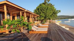 a row of lounge chairs on a wooden deck at Sunset Moyo Bungalows in Moyo Island