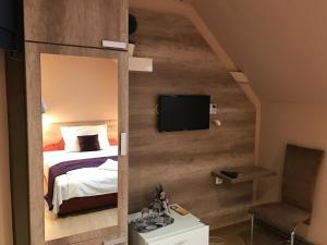 a bedroom with a bed and a tv on a wall at Abszolút Hotel és Panzió in Nyírbátor