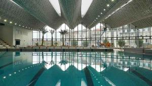 a large swimming pool in a building with a large window at Cocon entre centre ville autoroute in Reims