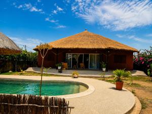 a hut with a swimming pool in front of it at Villa Farou in Mbour