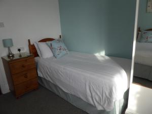 a bedroom with a white bed and a night stand at The Denewood in Sandown