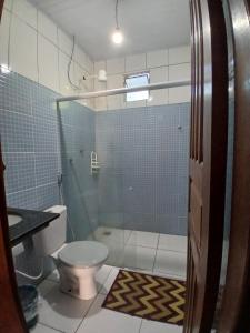 a bathroom with a toilet and a glass shower at Férias da Hora in Prado +8 photos