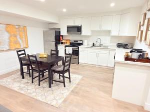 a kitchen with white cabinets and a table and chairs at Fairway Retreat Chilliwack in Chilliwack