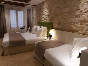 a hotel room with two beds and a stone wall at Hôtel De La Herse d'Or in Paris