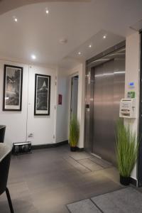 an office lobby with a door and two plants at Hôtel De La Herse d'Or in Paris