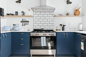 a kitchen with blue cabinets and a stove at The Tide & Seek House in Cape Town