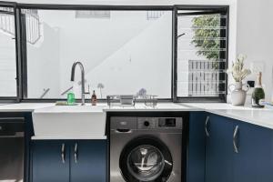 a kitchen with blue cabinets and a washing machine at The Tide & Seek House in Cape Town +57 photos