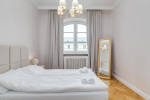 a white bedroom with a bed and a mirror at Quiet luxury at the Royal Route in Warsaw in Warsaw