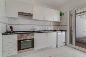 a white kitchen with white cabinets and appliances at Esfera I Calm Stay With Parking & Workspace in Caniço