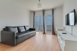a living room with a black leather couch and a television at Esfera I Calm Stay With Parking & Workspace in Caniço