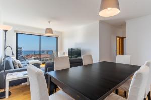 a dining room with a black table and white chairs at Jardins Do Oceano Ii Modern Stay Near Beach in Caniço