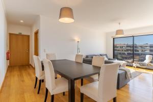 a dining room with a table and chairs and a couch at Jardins Do Oceano Ii Modern Stay Near Beach in Caniço +10 photos