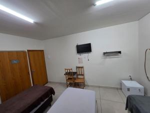a room with two beds and a tv on the wall at Suítes Caminho do Pantanal in Aquidauana