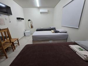 a room with two beds and a white wall at Suítes Caminho do Pantanal in Aquidauana