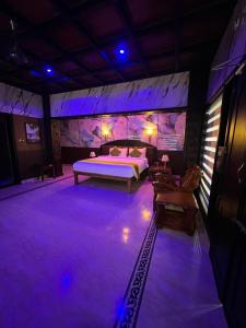 a bedroom with a bed on a stage with purple lights at Clifinn Wellness Beach Resort by nutmeg in Trivandrum