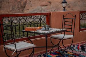 a table with two chairs and a table with food on it at Ijoukak Berber HomeStay in Ijjoukak