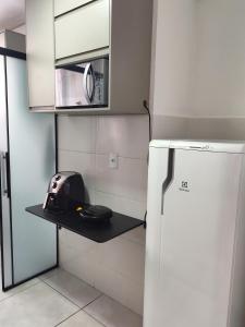 a small kitchen with a black shelf next to a refrigerator at Apartamento Moderno e Confortável in Lavras +9 photos