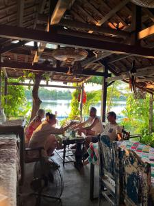 a group of people sitting at a table in a restaurant at Nguyet Bieu Riverside in Thôn Kim Long (1)