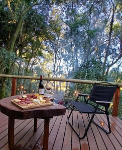 a picnic table with a bottle of wine and a chair on a deck at Cabana Cipó in Passo Fundo