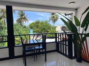 a balcony with a table and chairs and palm trees at Alyraa Sunset Mathiveri - Free Picnic Island Trip Included in Mathiveri