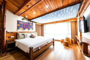 a bedroom with a bed and a flat screen tv at Windmoon Hillcourt Tianmen Vis Lodge in Zhangjiajie +85 photos