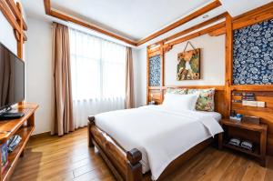 a bedroom with a bed and a flat screen tv at Windmoon Hillcourt Tianmen Vis Lodge in Zhangjiajie