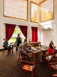 a group of people sitting at tables in a restaurant at Amore Beach Resort in Balapitiya
