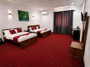 a hotel room with two beds and a red carpet at Amore Beach Resort in Balapitiya