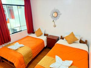 two beds in a room with orange sheets at Sunrise Guest House in Huaraz