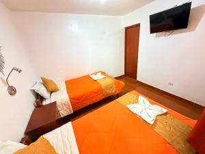 two beds in a room with a flat screen tv at Sunrise Guest House in Huaraz