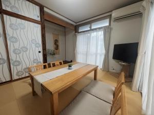 a dining room with a wooden table and a television at Forest Agata in Matsumoto