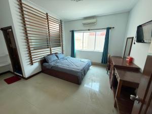 a bedroom with a bed and a desk and a window at White Castle in Siem Reap