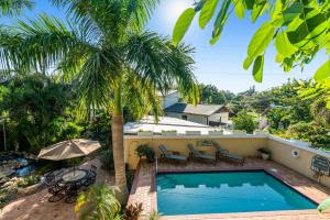 a pool with a palm tree next to a house at Banyan House Vacation Rentals in Venice