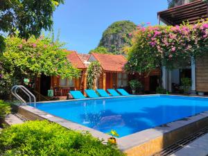 a swimming pool in front of a house with flowers at Tam Coc Sunshine Homestay in Ninh Binh