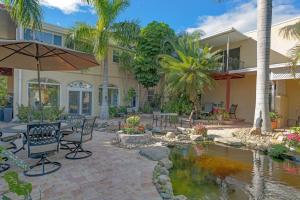 a patio with chairs and an umbrella next to a pond at Banyan House Vacation Rentals in Venice