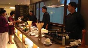 a group of people standing in a kitchen preparing food at GT Hotel Bacolod in Bacolod
