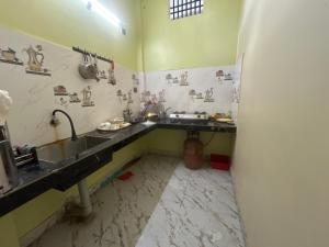 a kitchen with a sink and a person sitting on the floor at JAJABAR Homestay in Dum Duma +32 photos